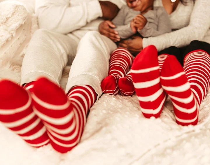 family sitting on the bed with red and white socks